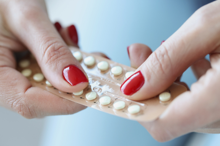 kobieta trzymająca blister z hormonalnymi pigułkami antykoncepcyjnymi